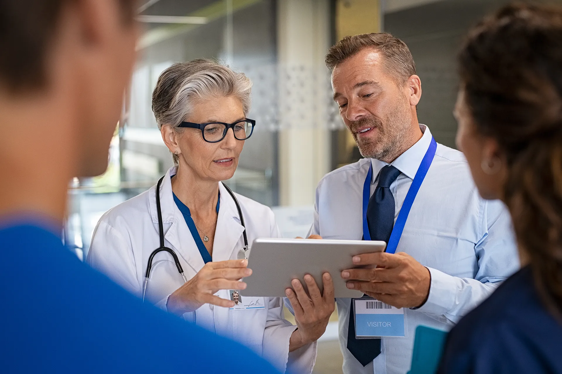 Healthcare consultant collaborating with a doctor on a tablet, discussing strategic solutions for medical practices.